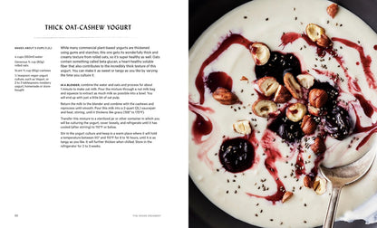 A bowl of thick, creamy white yogurt with berry sauce, hazelnuts, and chia seeds sits beside a recipe for oat-cashew yogurt inspired by Vegan Creamery by Miyoko Schinner (Signed & Personalized) from Yu & Me Books. A spoon rests in the bowl.